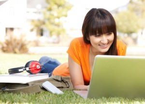 Total English Online. Women learning English in the park on a laptop.
